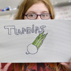 Summer Wasilowski shows off a crop sign she made for the club's garden to be used later this Spring.