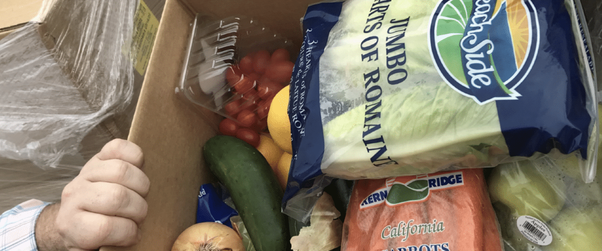 A hand reaching into a box of produce